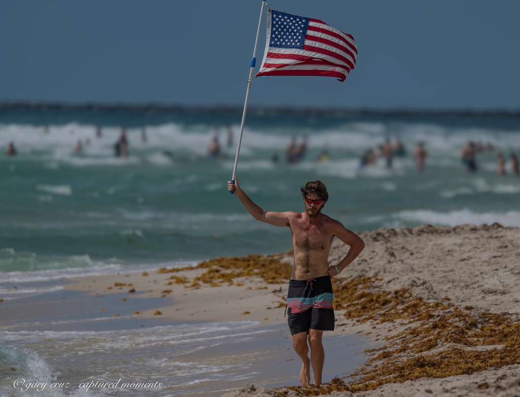 Glen Bradford holding the American flag, walking toward camera, Miami Beach Memorial Day 2026