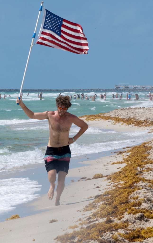 Glen Bradford sprinting with the American flag held high, Miami Beach Memorial Day 2026