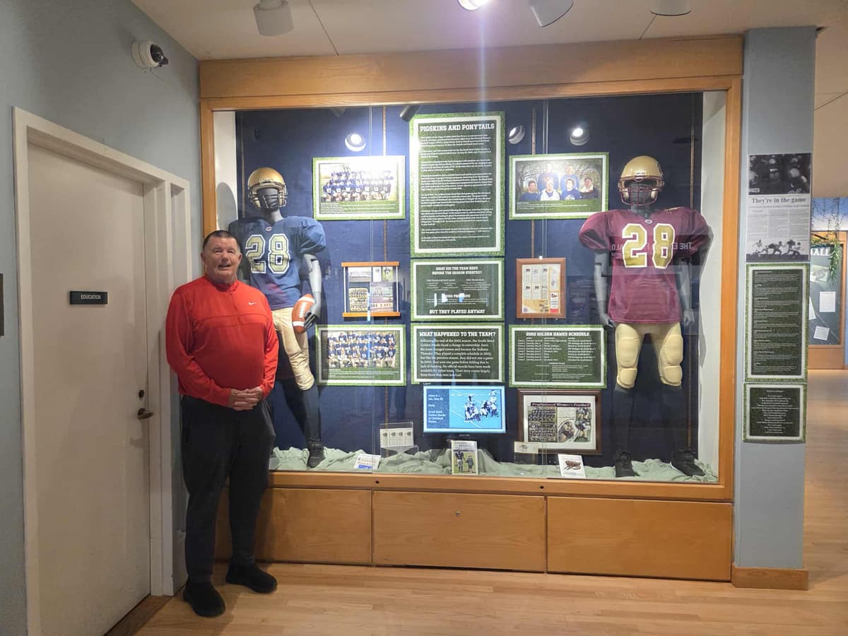 Mark Bradford standing next to the full Pigskins and Ponytails exhibit at The History Museum in South Bend